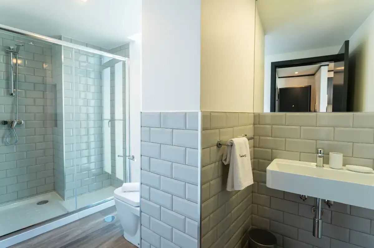 A modern bathroom with a glass-enclosed shower, a toilet, and a sink with a mirror above it.
