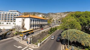 Une vue de rue avec un bâtiment doté d’un toit rouge, un autobus jaune et un ciel bleu dégagé.