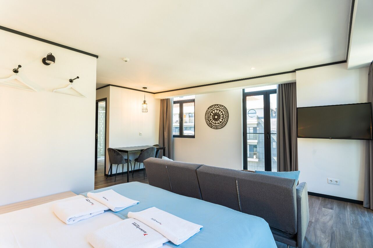 Quarto de hotel moderno com cama, sofá, escrivaninha e televisão.