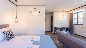 A modern hotel room with a bed, a sofa, a desk, and two pendant lights.