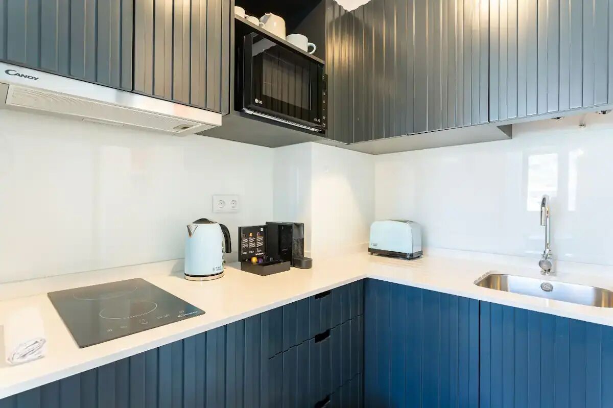A modern kitchen with a microwave, toaster, kettle, and induction cooktop.