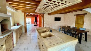 Une cuisine spacieuse avec un grand îlot central, des poutres en bois au plafond et une cheminée.