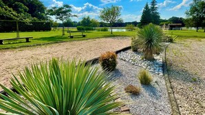 Un parc avec un sentier de gravier, des bancs et une variété de plantes.