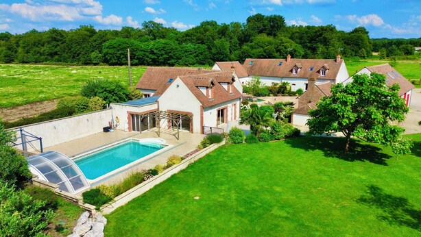 Une grande maison avec une piscine, un patio couvert et une pelouse bien entretenue.
