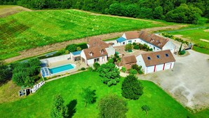 Une vue aérienne d’un vaste domaine comprenant plusieurs bâtiments, une piscine et de vastes pelouses verdoyantes.