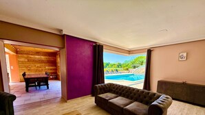 Un salon avec une table basse en bois, un canapé marron et une vue sur une piscine.