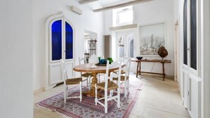 A dining area with a round wooden table, white chairs, and a patterned rug. - Garibaldi Luxury, in complete luxury and relaxation (Otranto)
