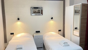 Een tweepersoonskamer met twee bedden, een nachtkastje, een spiegel en een afbeelding aan de muur.