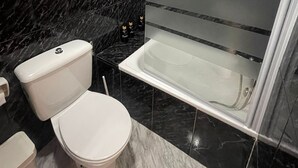 Een moderne badkamer met een toilet, een bad en een douche.