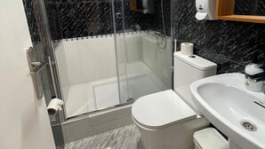 Een moderne badkamer met een douchecabine van glas, een toilet en een wastafel.