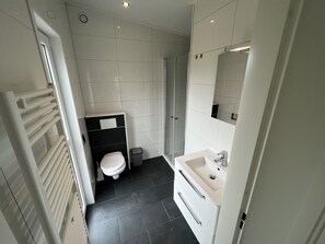 A modern bathroom with a toilet, sink, and shower. - Enticing Chalet Beachside (Hellevoetsluis)