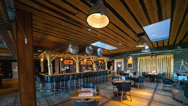 Un restaurant doté d’un plancher en bois, d’un bar et de tables avec des chaises.