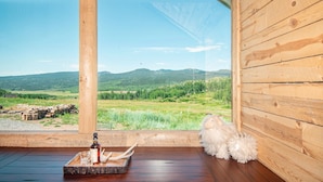 A wooden cabin with a large window offering a view of a green landscape and mountains. - EML 3 Colorow (Paonia)