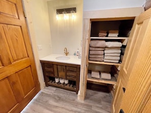 Ein Badezimmer mit Waschtisch aus Holz, einem Waschbecken, einem Spiegel und einem Handtuchhalter.