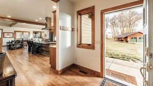 Eine geräumige Küche mit Holzboden, eine Essecke mit einer Ledersofa und ein Blick auf eine Garage und einen Garten durch ein großes Fenster.