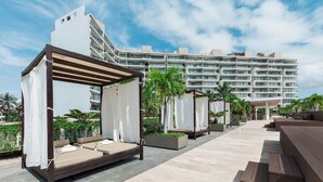 Ett semesterhotell med utomhusområden med sittplatser, en pool och en stor hotellbyggnad i bakgrunden.