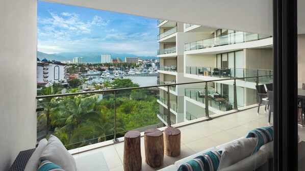 Un appartement moderne doté d’un balcon offrant une vue sur un port de plaisance et sur le paysage urbain.