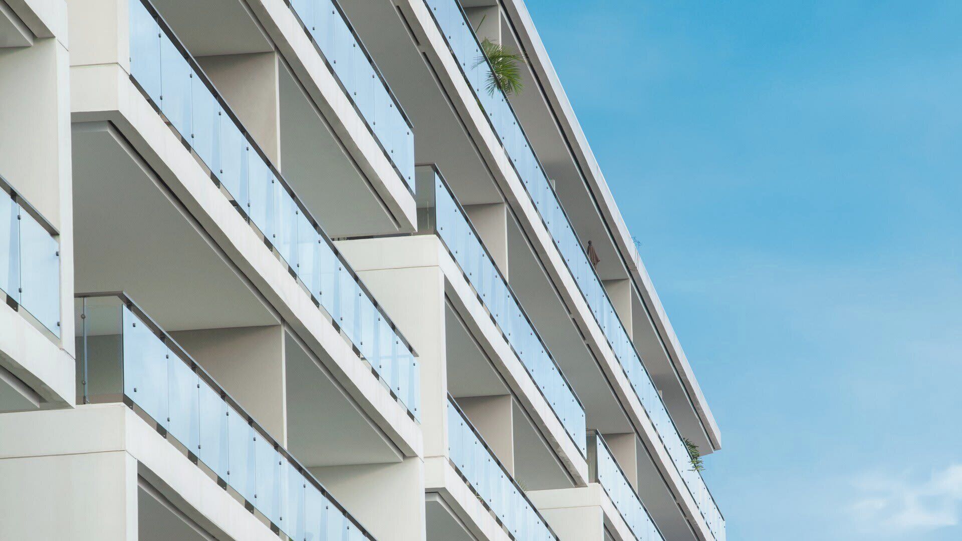A multi-story building with balconies, clear sky, and a plant on one balcony.