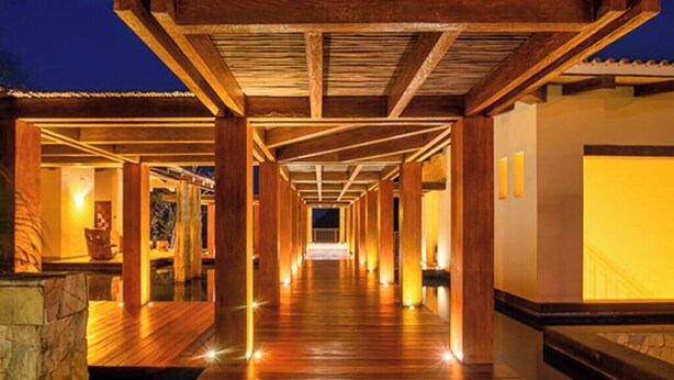 Un pasillo de madera con una cubierta, que conduce a un edificio con tejado de baldosas.