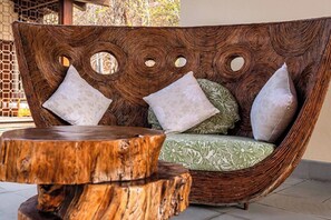 A wicker sofa with circular cutouts and a round wooden table. - Curamoria Collection Celeste Huatulco (Santa María Huatulco)