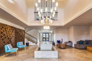 Un hall d’entrée spacieux avec une fontaine en marbre, un espace salon et un escalier.