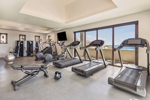 Une salle de sport moderne équipée de tapis de course, de vélos elliptiques et de matériel de musculation.