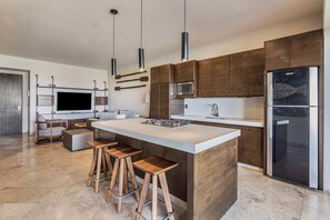 Une cuisine moderne dotée d’un grand îlot central, de tabourets de bar, d’un four encastré et d’un réfrigérateur.