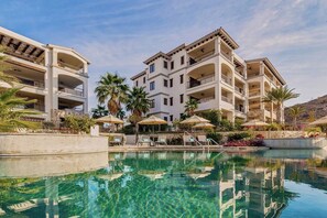 Un hôtel doté d’une piscine, de plusieurs balcons et de palmiers.