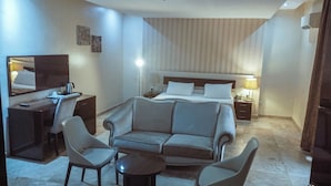 A hotel room with a large bed, a sofa, two armchairs, a desk, and a small table. - Fullmoon Hotels Owerri (Owerri)