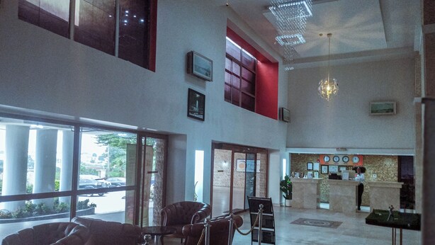 A spacious lobby with a reception desk, seating area, and large windows. - Fullmoon Hotels Owerri (Owerri)