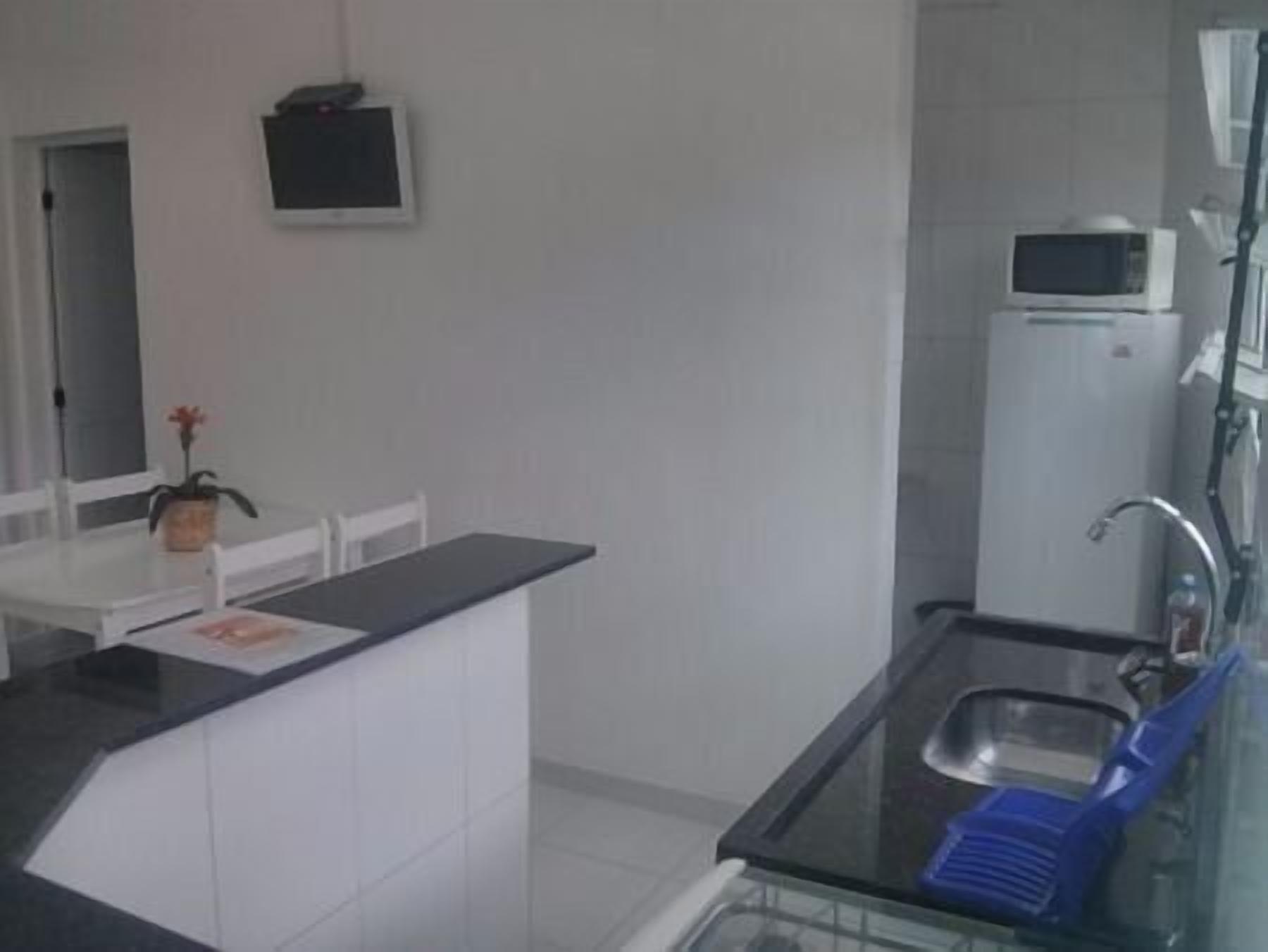 A compact kitchen with a black countertop, a white sink, and a microwave.