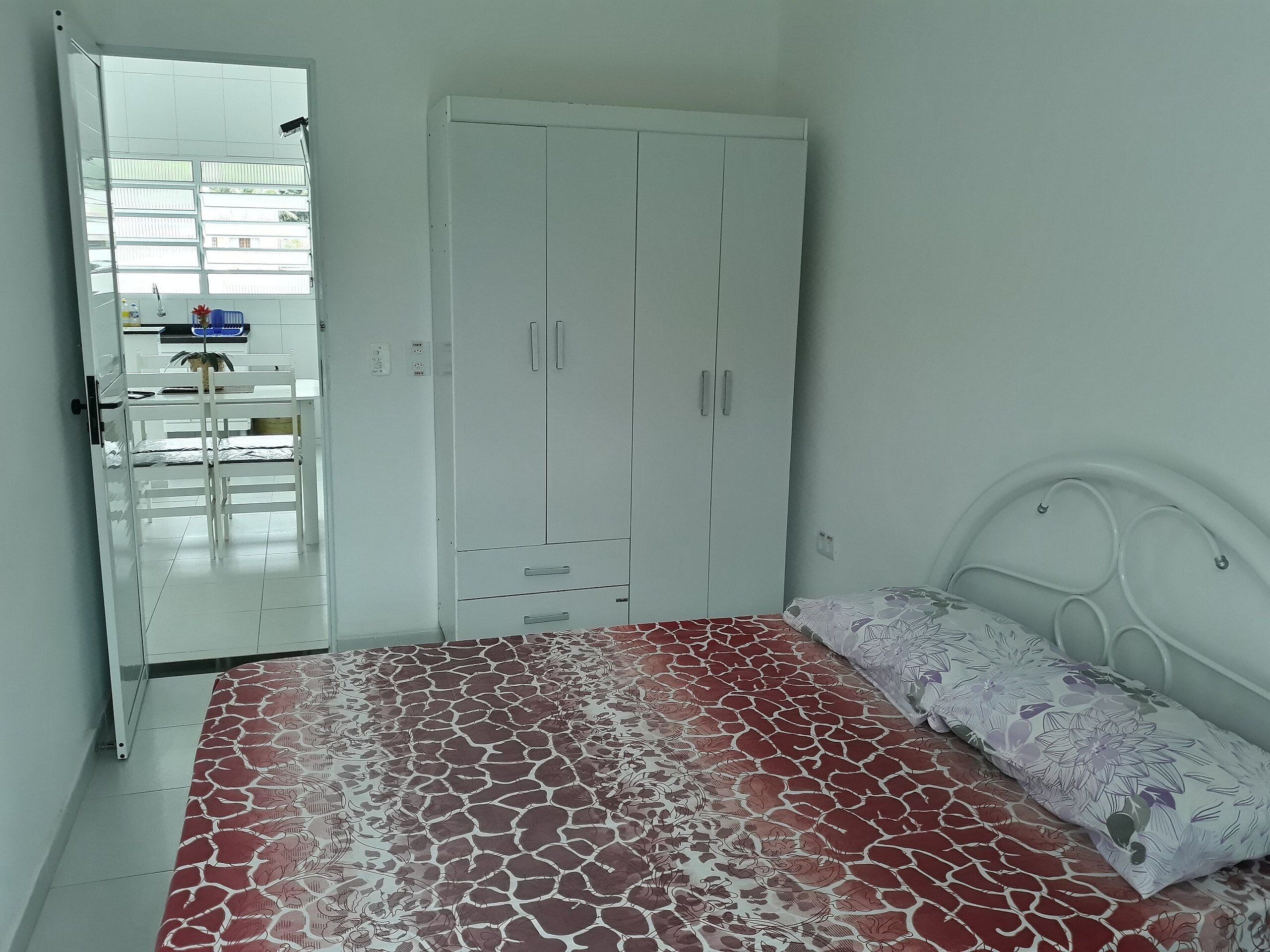 A bedroom with a bed, a white wardrobe, and a window.