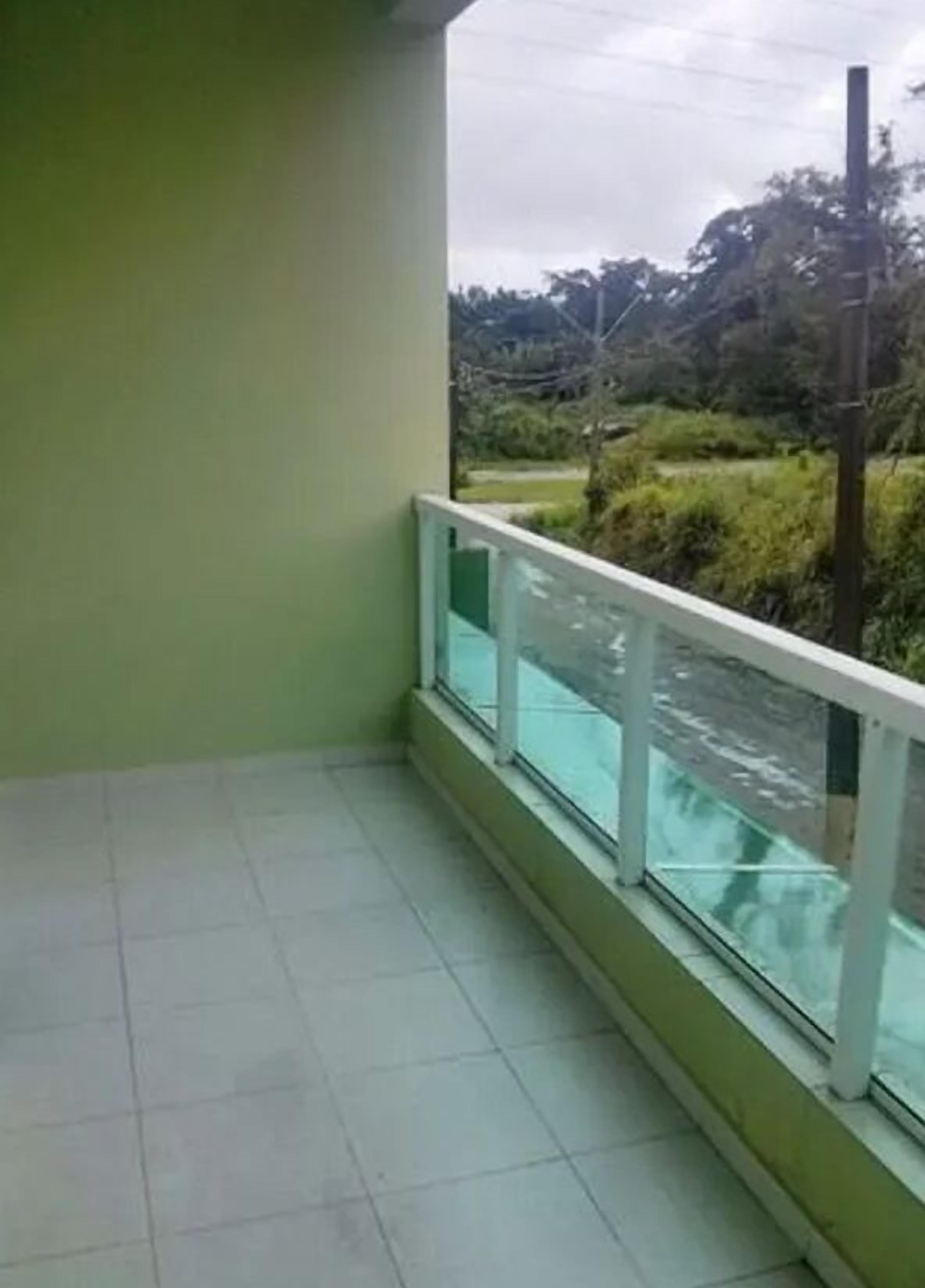 Un balcon avec un sol carrelé et une balustrade en verre.