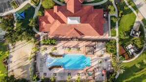 An aerial view of a hotel with a swimming pool, a covered patio, and a parking lot. - UpstaySleeps20ThemeRoomsPoolHotTubTheatr (Kissimmee)