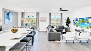A modern open-plan living space with a kitchen, dining area, and seating area. - UpstaySleeps20ThemeRoomsPoolHotTubTheatr (Kissimmee)