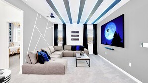 A modern living room with a sectional sofa, a coffee table, and a flat-screen TV mounted on the wall. - UpstaySleeps20ThemeRoomsPoolHotTubTheatr (Kissimmee)