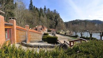 A lakeside property with a brick building, stone steps, and a wooden deck overlooking the water.