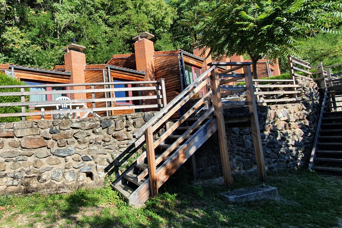 Una rústica escalera de piedra que lleva a una cabaña de madera con barandilla de metal.