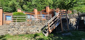 Una rústica escalera de piedra que lleva a una cabaña de madera con barandilla de metal.