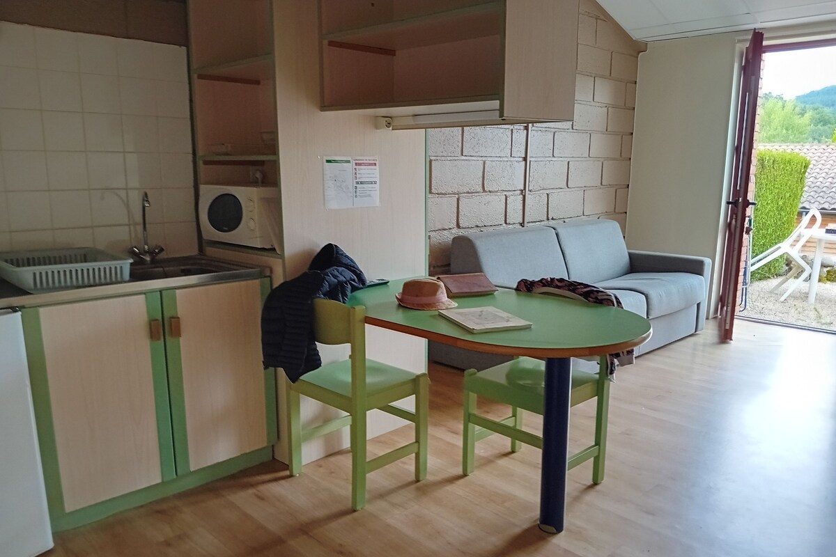 A compact kitchen with a sink, a stove, and a dining area with a table and two chairs.