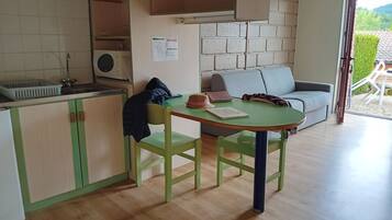 A compact living space with a kitchenette, a dining table, and a sofa.