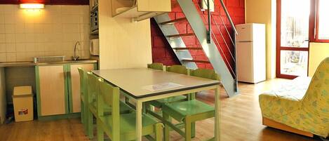 Une cuisine de taille réduite comprenant un coin repas, un escalier et une fenêtre.