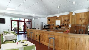 Un ristorante con un bancone in legno, sedie verdi e tavoli con tovaglie bianche.