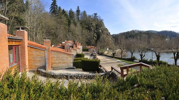 Una proprietà sul lago con un edificio in mattoni, gradini in pietra e un pontile di legno che si affaccia sull'acqua.