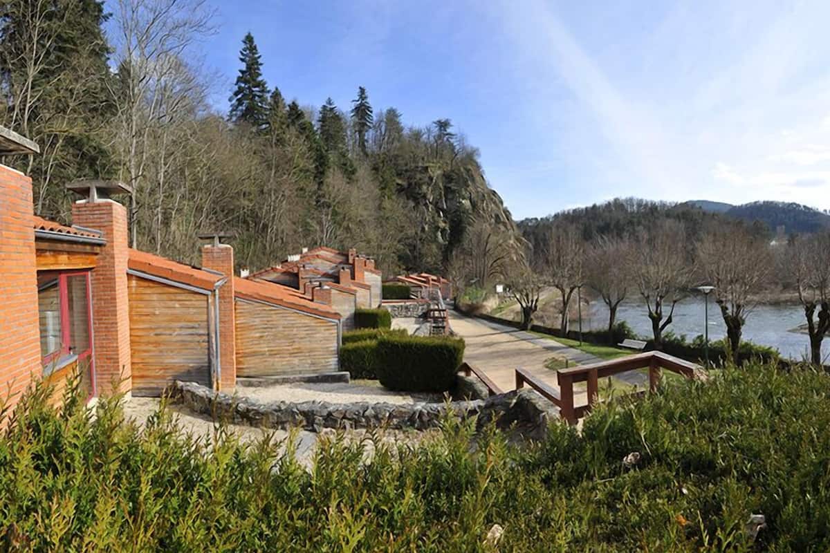 A lakeside property with a brick building, stone steps, and a wooden deck overlooking the water.