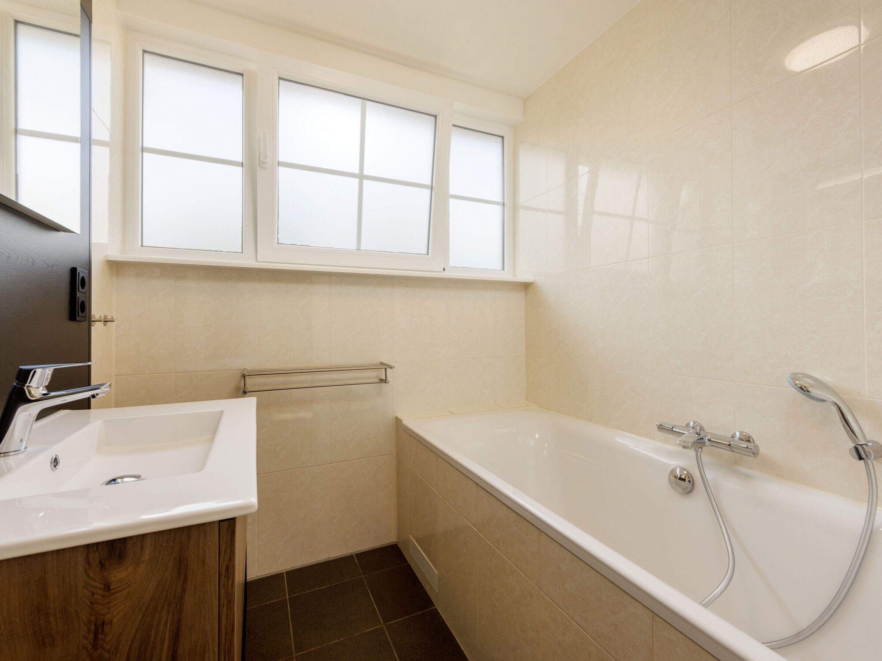 A bathroom with a bathtub, a sink, and a window above the sink.