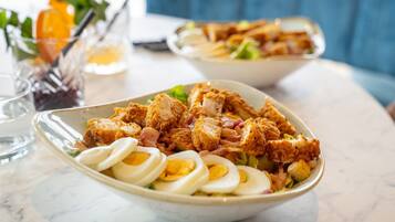 Un bol rempli de nourriture, comprenant du poulet frit, des œufs et des légumes, posé sur une table en marbre.