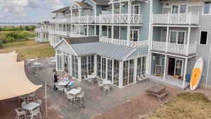Un bâtiment situé sur la côte, doté de nombreux balcons, d’un espace extérieur aménagé pour s’asseoir et d’une enseigne indiquant la présence d’un restaurant.