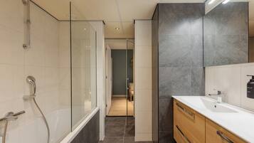 Un baño moderno con cabina de ducha de vidrio, tocador de madera y un espejo grande.