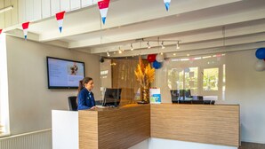 A reception desk with a computer, a framed sign, and a window with balloons.